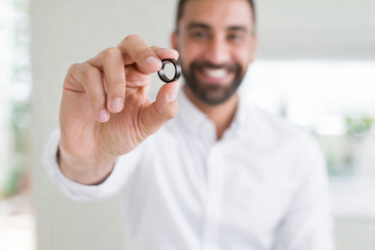 Smiling man holding a Smart Ring, showcasing its sleek design and modern features.